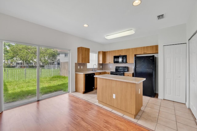 kitchen with backsplash, a center island, sink, light hardwood / wood-style flooring, and black appliances