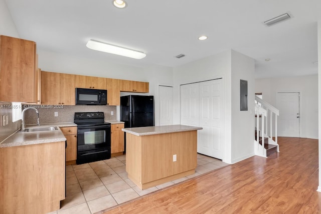 kitchen featuring light hardwood / wood-style flooring, tasteful backsplash, sink, black appliances, and a center island