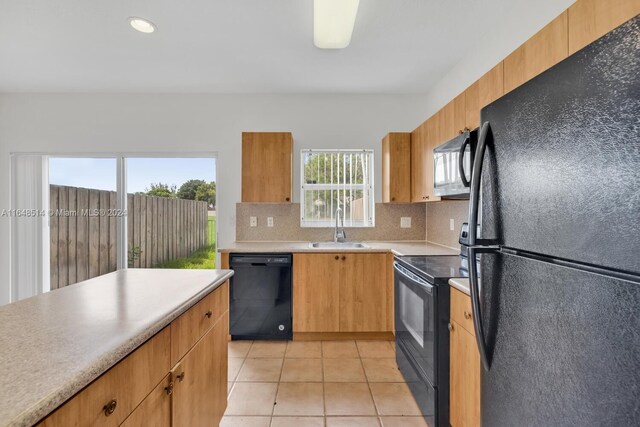 kitchen with sink, decorative backsplash, light tile patterned floors, and black appliances