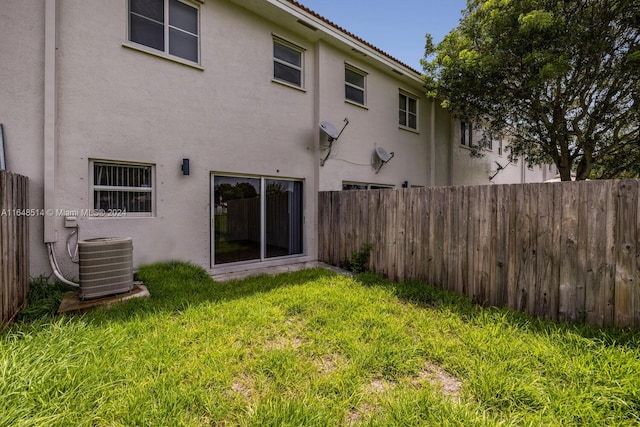 rear view of property featuring cooling unit and a yard