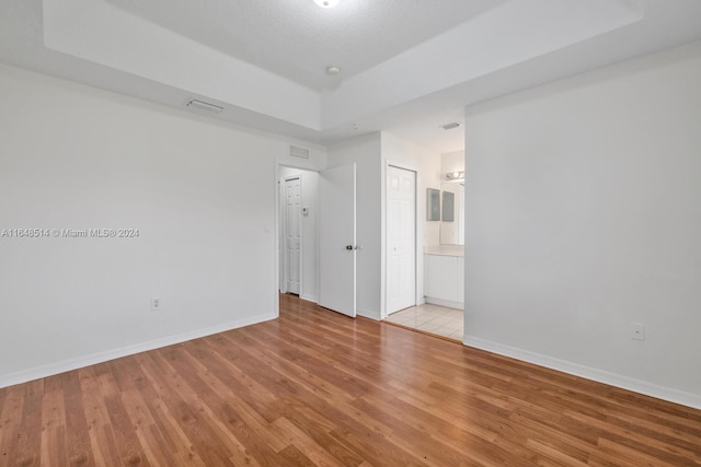 spare room featuring light wood-type flooring and a raised ceiling