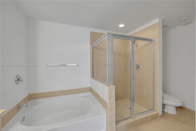 bathroom featuring toilet, tile patterned floors, and shower with separate bathtub