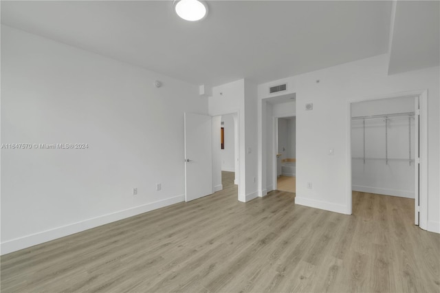 unfurnished bedroom with light hardwood / wood-style flooring, a walk in closet, and a closet