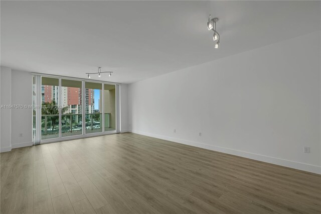 unfurnished room with rail lighting, light hardwood / wood-style flooring, and a wall of windows