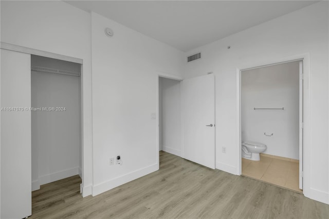 unfurnished bedroom with a closet, light hardwood / wood-style floors, and ensuite bath