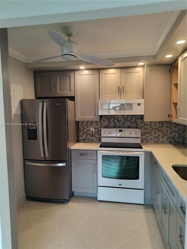 kitchen with light tile patterned floors, decorative backsplash, white appliances, ceiling fan, and crown molding