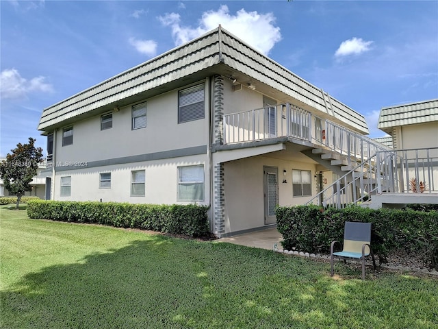 rear view of house featuring a balcony and a yard