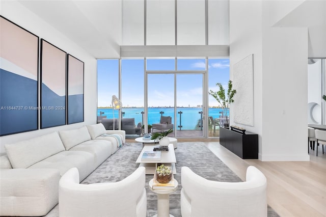 living room with a water view, a high ceiling, and light hardwood / wood-style flooring