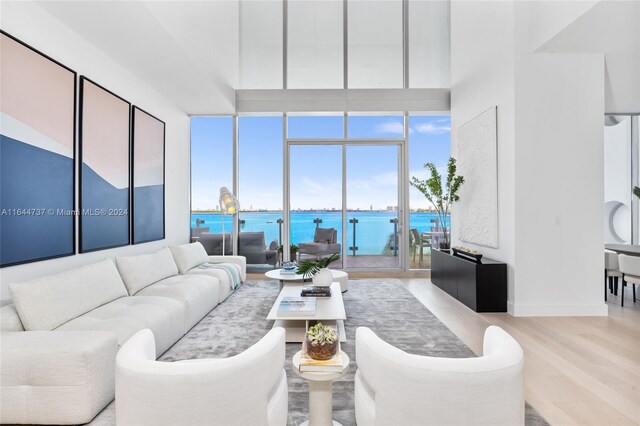 living area featuring a water view, baseboards, wood finished floors, and expansive windows