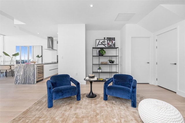 sitting room with light wood-type flooring, lofted ceiling, and wine cooler