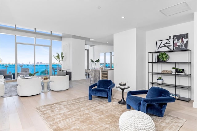 sitting room with light wood-type flooring, a water view, and a wealth of natural light