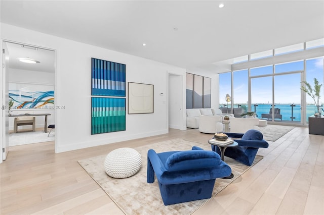 living area with baseboards, floor to ceiling windows, a water view, and wood finished floors
