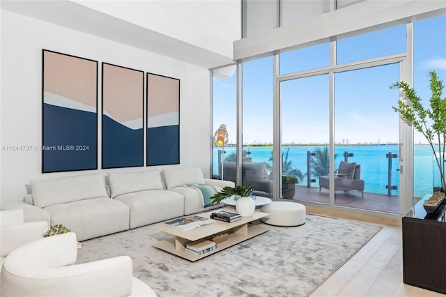 living room with floor to ceiling windows, a water view, wood finished floors, and a towering ceiling