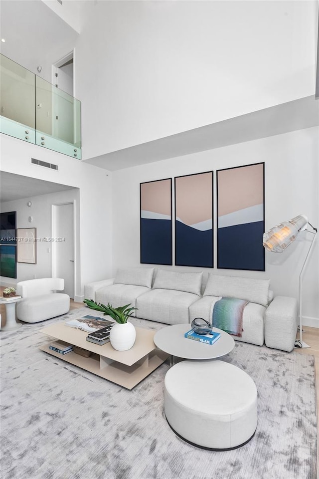 living room with baseboards, a high ceiling, wood finished floors, and visible vents