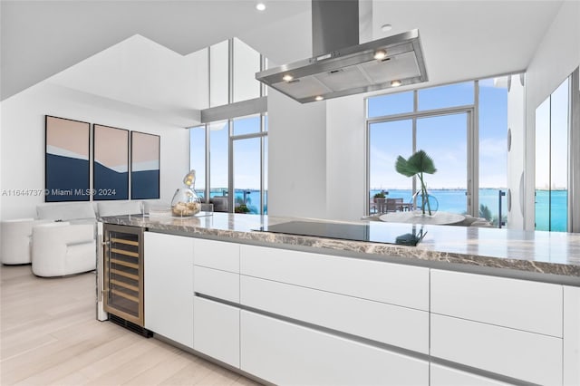 kitchen with light stone countertops, island range hood, and white cabinetry