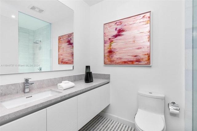 bathroom featuring tile patterned flooring, vanity, toilet, and tiled shower