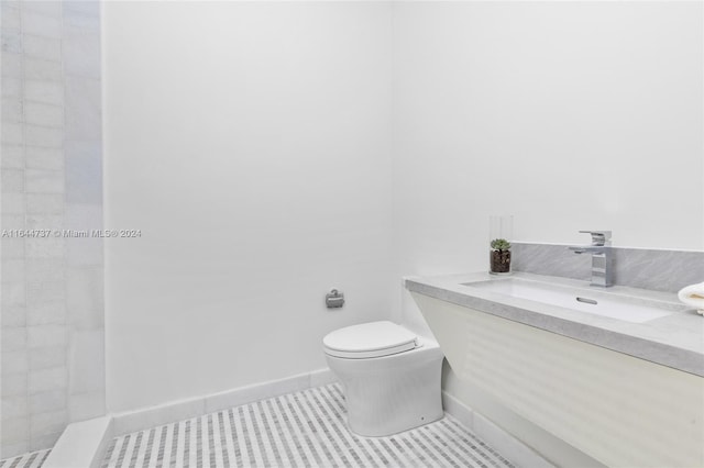 bathroom featuring tile patterned flooring, vanity, toilet, and tiled shower