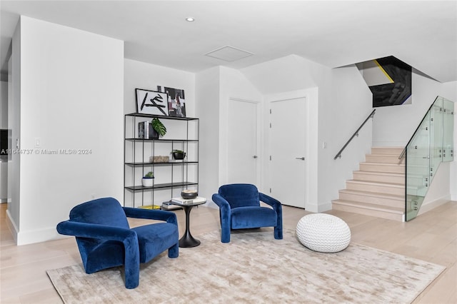 living area featuring baseboards, stairs, and wood finished floors