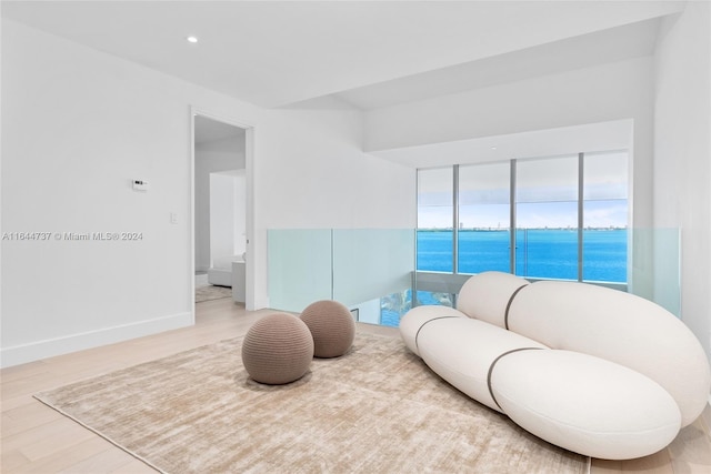 sitting room with a water view and light hardwood / wood-style floors