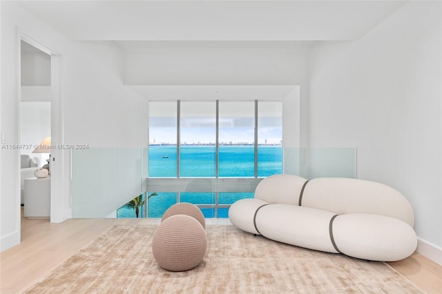 sitting room featuring a water view, baseboards, and wood finished floors