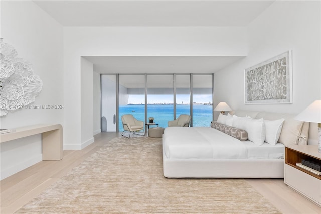 bedroom featuring a water view, baseboards, and wood finished floors