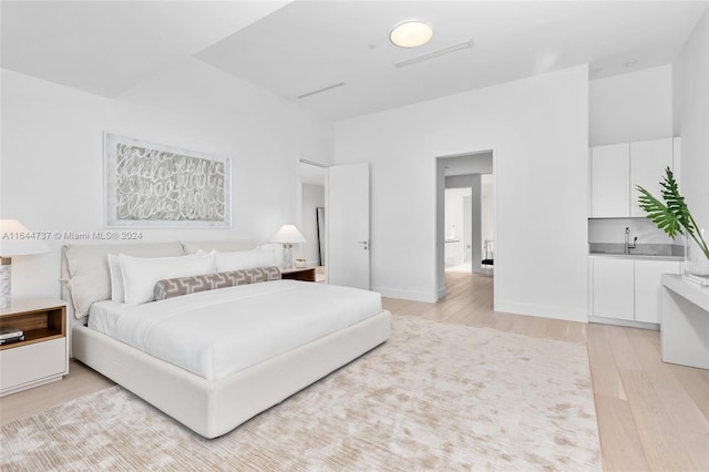 bedroom with baseboards, a sink, and light wood-type flooring