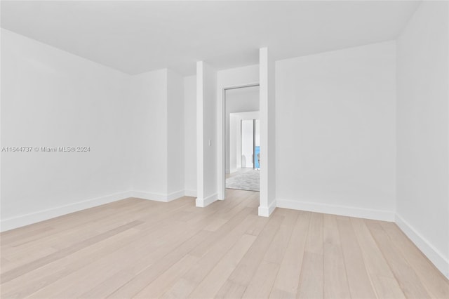 spare room featuring baseboards and light wood finished floors