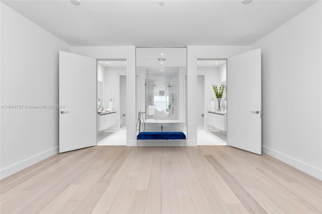 unfurnished bedroom featuring baseboards, ensuite bath, and wood finished floors