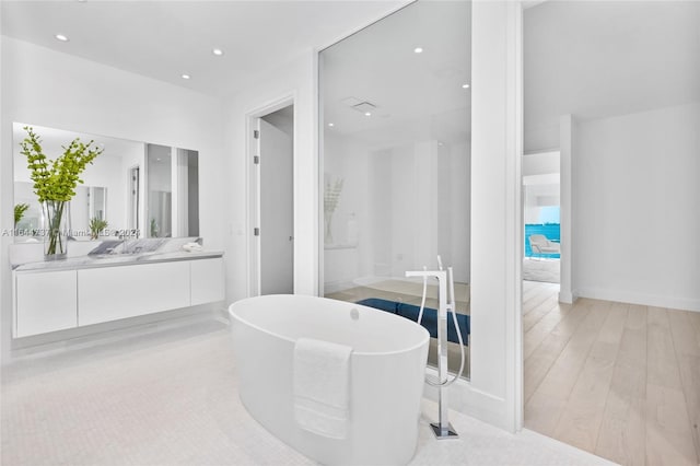 bathroom featuring vanity, hardwood / wood-style flooring, and a washtub