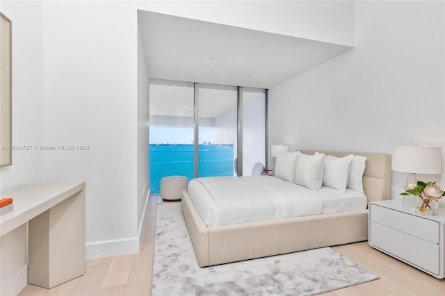 bedroom featuring light wood-type flooring, a wall of windows, and access to outside