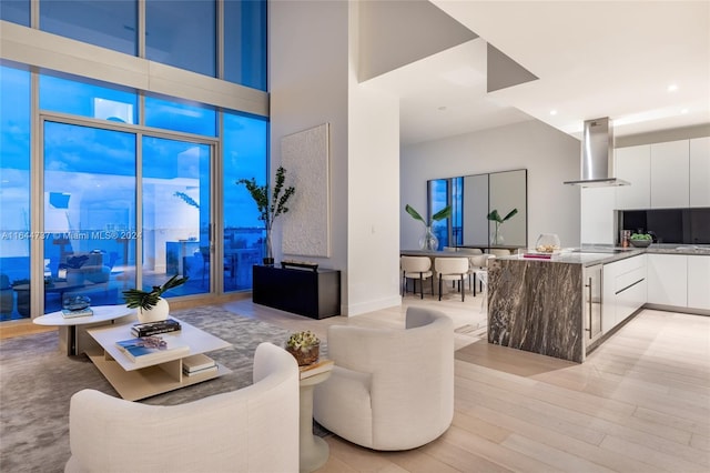 living area with light wood-style floors, a high ceiling, and recessed lighting