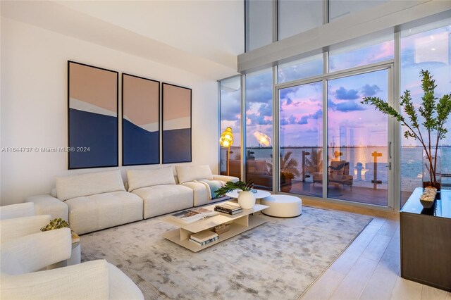 living room with a water view, light hardwood / wood-style floors, and a towering ceiling