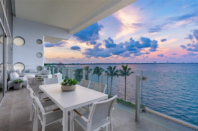 balcony at dusk with a water view and outdoor dining space