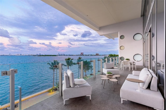 balcony at dusk featuring a water view