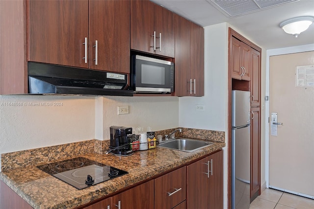 kitchen with dark stone countertops, appliances with stainless steel finishes, light tile patterned floors, and sink