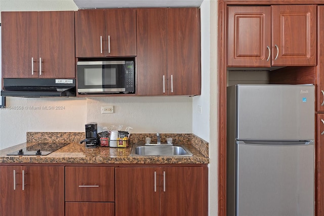 kitchen with sink, appliances with stainless steel finishes, and dark stone counters