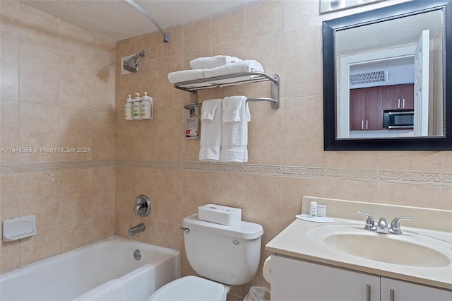 full bathroom with vanity, toilet, tile walls, and tiled shower / bath