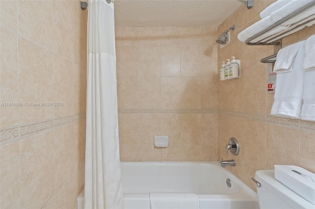 bathroom featuring a textured ceiling, shower / bath combo with shower curtain, and toilet