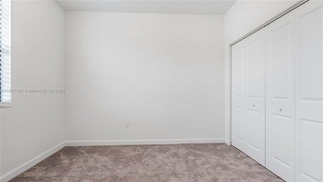 unfurnished bedroom featuring a closet and light colored carpet