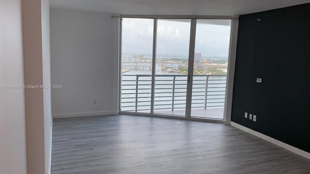 spare room with a wall of windows and dark hardwood / wood-style floors