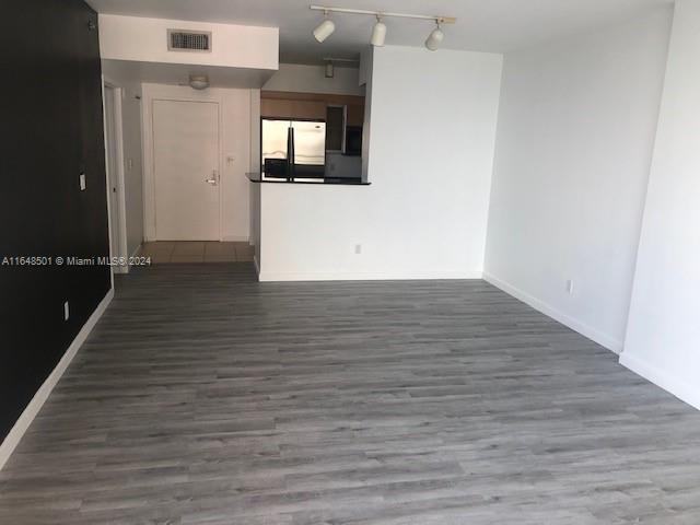 spare room featuring track lighting and dark wood-type flooring