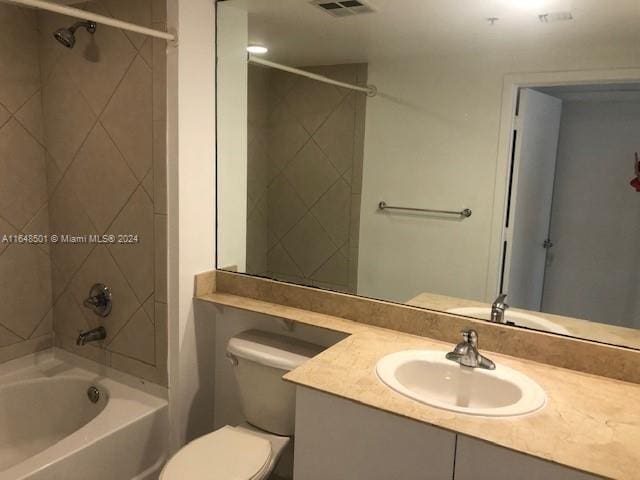 full bathroom featuring tiled shower / bath combo, toilet, and vanity