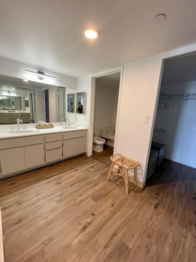 bathroom with double vanity, wood finished floors, a bidet, and a sink