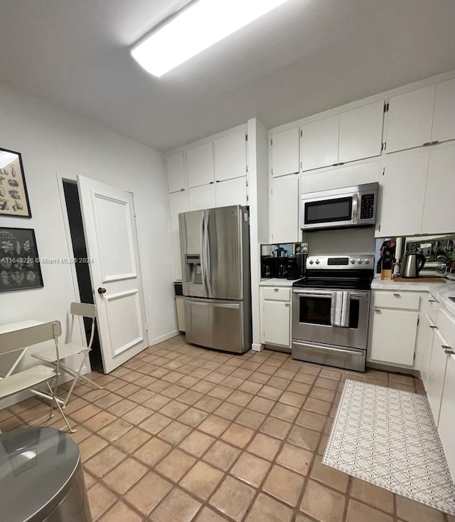 kitchen featuring light countertops, appliances with stainless steel finishes, light tile patterned flooring, and white cabinets