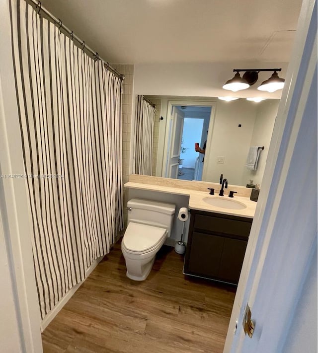 bathroom featuring vanity, a shower with shower curtain, wood finished floors, and toilet