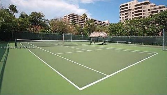 view of tennis court with community basketball court and fence