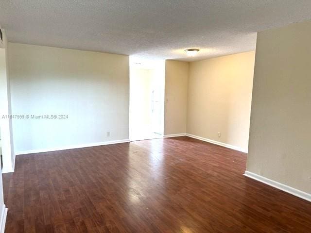 empty room featuring dark hardwood / wood-style flooring and a textured ceiling