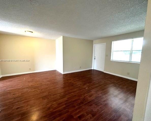 spare room featuring dark wood-type flooring and a textured ceiling