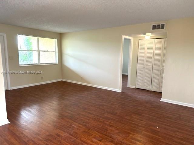 unfurnished bedroom with a closet, a textured ceiling, and dark hardwood / wood-style flooring