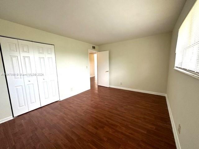 unfurnished bedroom with a closet and dark wood-type flooring